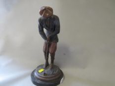 A cast metal figure of a traditional golfer
