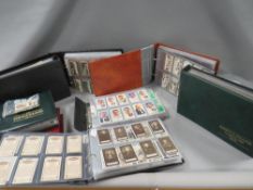 A collection of cigarette cards in various albums