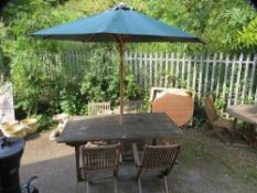 A large rectangle hardwood garden table set to include four folding chairs and a large parasol