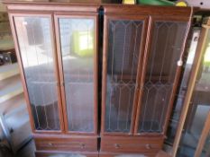 Two modern glazed tall bookshelves with glass shelves and drawer