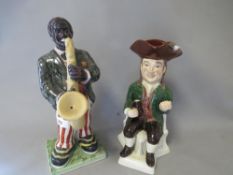 A modern reproduction figure of a saxophone player together with a toby jug