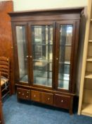 A modern glazed display cabinet with three drawers below