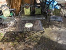 A wrought iron garden set consisting of a table, two chairs and a bench
