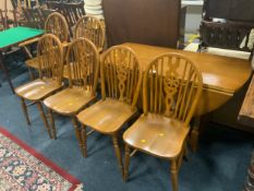 An oak drop leaf table together with six wheel back chairs