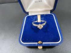 An 18ct white metal four claw set diamond solitaire ring (diamond showing colour and inclusions to