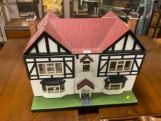 A rustic children’s dolls house with a small quantity of furniture