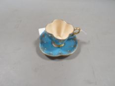 An antique Coalport quatrefoil blue gilded cup and saucer