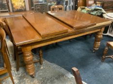 A large oak extending Edwardian dining table with four assorted extra leaves