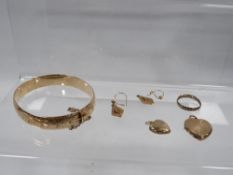 A bag of yellow plated metal jewellery to include a gold plated metal core bangle, lockets etc