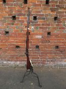 A vintage flintlock rifle converted to a standard lamp with bent wrought iron base