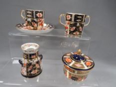 Four pieces of Royal Crown Derby Imari pattern to include twin handled milk churn, loving cup,