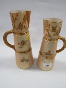 A pair of Royal Worcester blush ivory graduating jugs with gilded handles