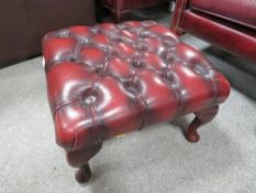An oxblood red leather chesterfield style footstool