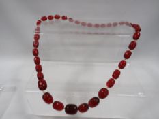 A string of individually knotted cherry coloured beads