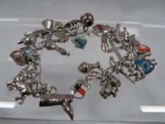 A silver charm bracelet with many charms approx. weight 70g