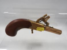 An antique replica flintlock pistol in brass with wooden grip