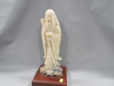 An Oriental style carved stone figure of robed man holding peaches