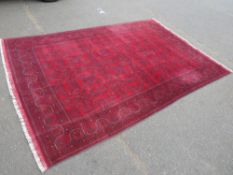 A large red Afghan style rug - approx. 300 x 200 cm