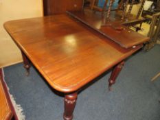 A small Victorian mahogany wind-out dining table raised on fluted supports with a spare leaf -