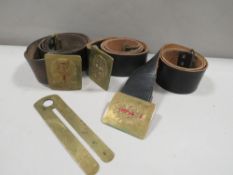 Three vintage leather military belts together with a brass button stick