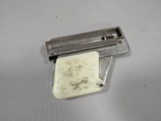 A vintage 'Imco, Gunlite' cigarette lighter, with white plastic grips