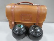A cased pair of lawn bowls and accessories