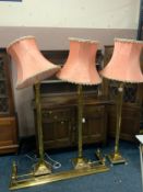 A set of three brass Corinthian column standard lamps with shades, together with an extending
