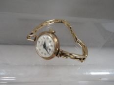 A 9 carat gold wrist watch on an expandable yellow metal bracelet