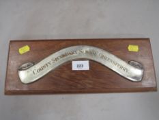 A white metal strip on wooden plaque inscribed 'County Secondary School, Queensferry'
