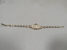 A hallmarked 18k gold wrist watch on a gold plated bracelet