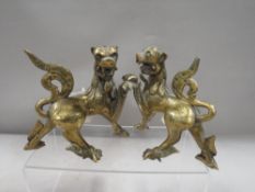 A pair of Oriental brass / bronze guardian dog figures, with green glass inlays