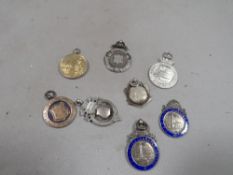 A collection of 8 hallmarked silver fobs and medallions