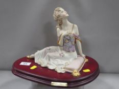 A Capodimonte figure of a lady sitting on a cushion