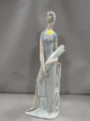 A tall Lladro figure of a lady carrying flowers