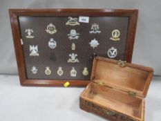 A framed display of military badges and a carved treen box