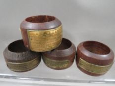 A set of four teak napkin rings from ships timber each with a named brass plaque consisting of HMS