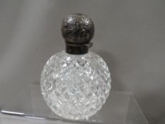 A large white metal topped cut glass scent bottle
