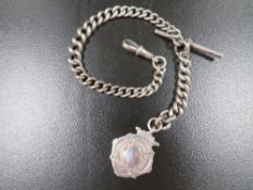 An antique silver pocket watch chain with fob medal