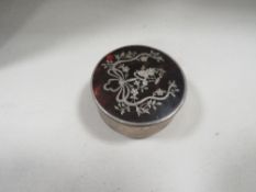 A circular hallmarked silver box with inlaid tortoiseshell lid