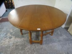 A modern oak finish round dropleaf gateleg dining table