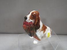 A Royal Doulton figure of a liver and white spaniel carrying a pheasant HN1028 A/F - tail has been