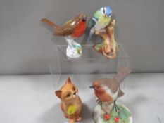 A Royal Doulton seated Ginger cat together with three assorted bird figures one A/F