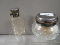 A hallmarked silver topped dressing table jar together with a white metal topped scent bottle