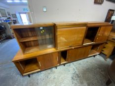 A mid century teak modular bookcase system comprising of two cabinets with feet and three further