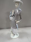 A Lladro figure of a lady holding a basket and a parasol