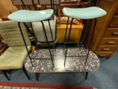 A mid century oval formica topped coffee table together with two stools