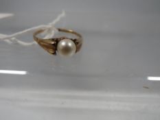 An unmarked yellow metal ring set with a pearl
