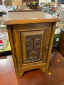 A small carved oak bedside cupboard