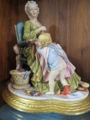 A capodimonte porcelain figure of a Mother darning a sock with children playing around her A/F