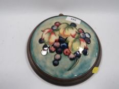 A circular Moorcroft plaque set on wooden wall hanging mount